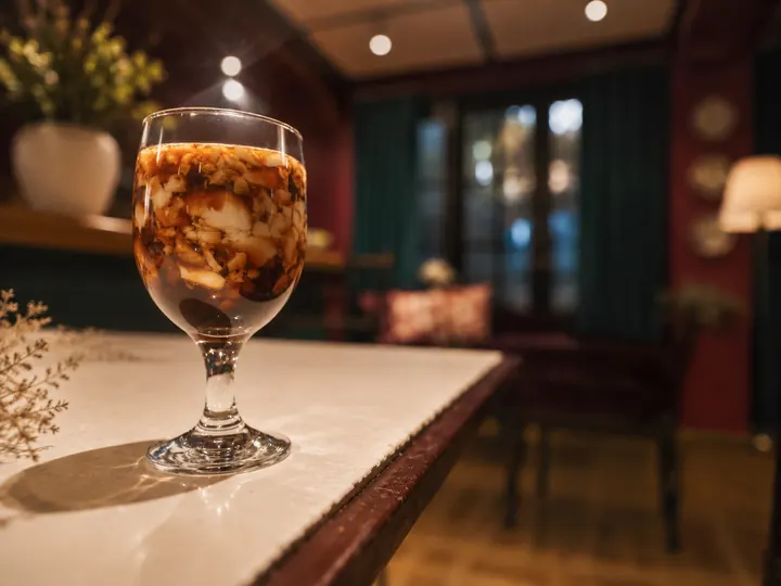 A cocktail on the marble bar top in the dim, red-walled Speakeasy Bar