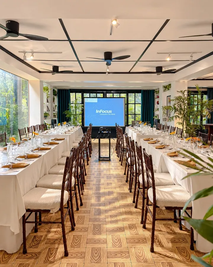 The main dining hall set with long tables and a screen for a company event