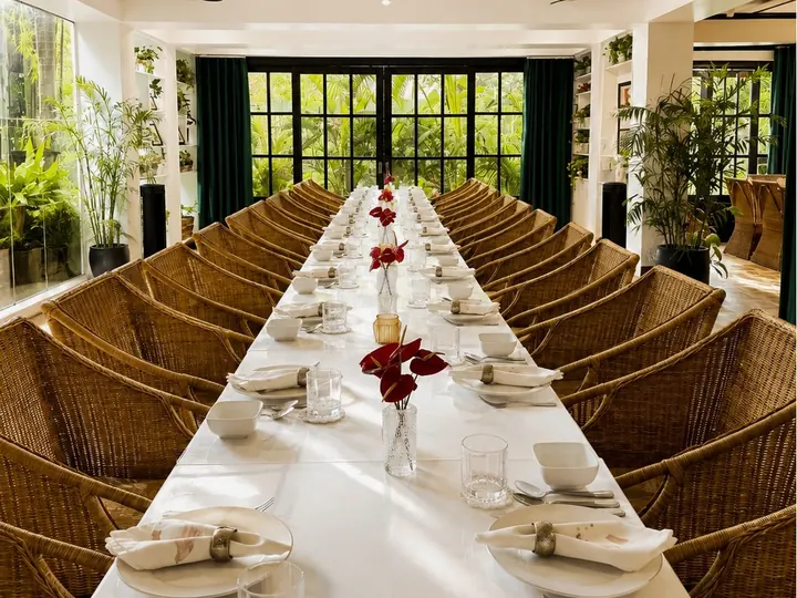 One long table down the main dining room, lined with rattan chairs, windows onto the garden at the end