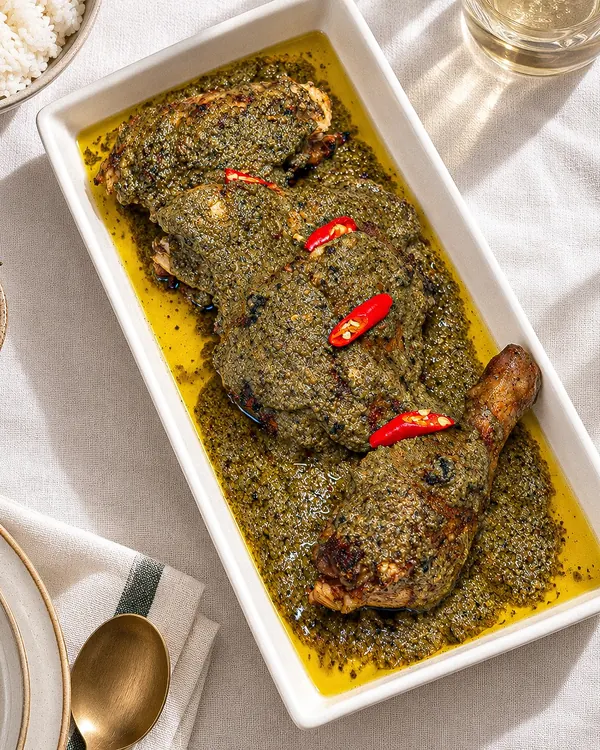 Chicken piyanggang in a dark green-black coconut sauce, topped with red chilies